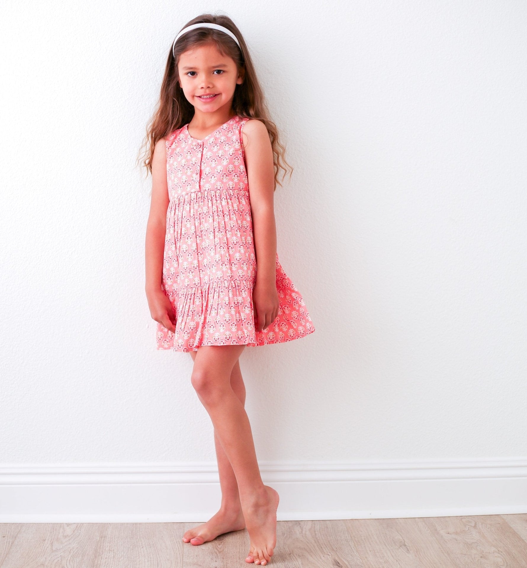 Hot pink baby dress with yellow and pink floral print, ruffle detail, and back-button pull-on style.
