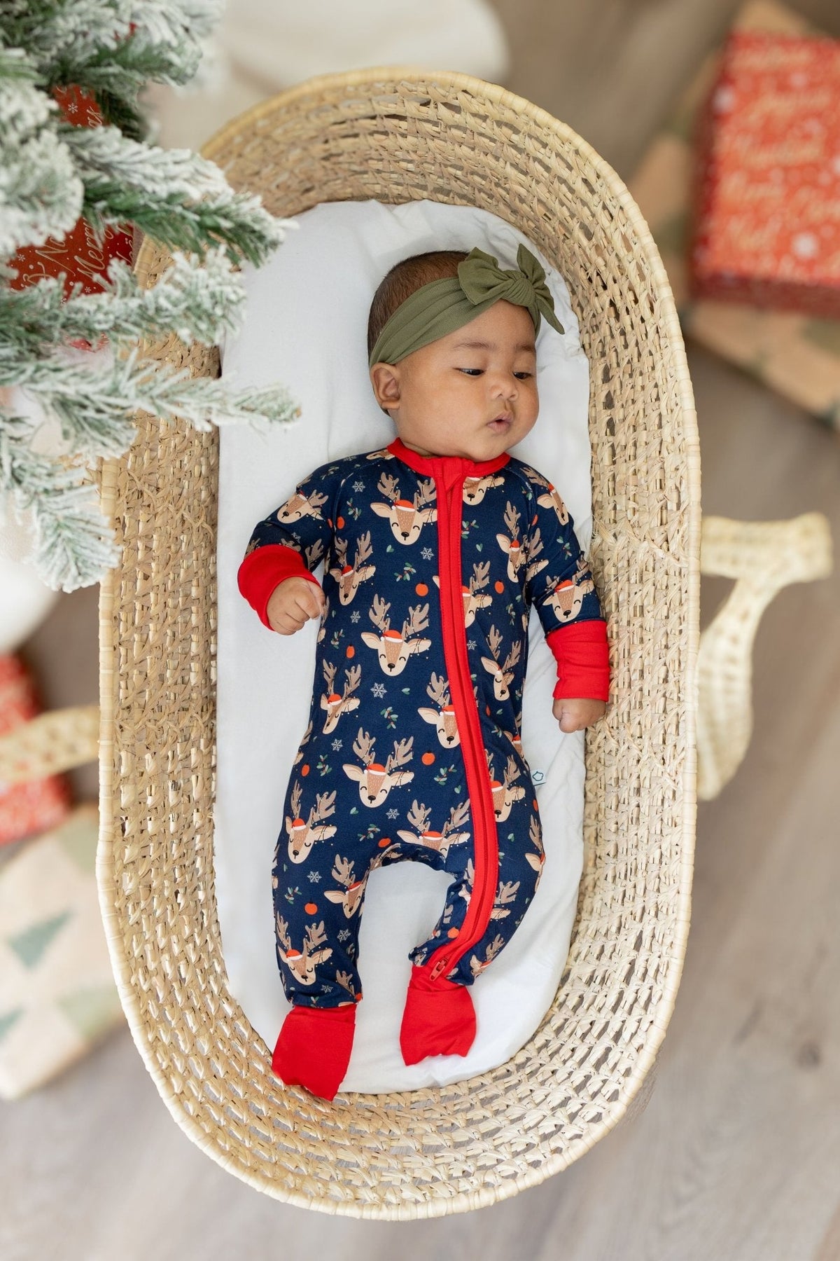 Baby zipper romper covered in reindeer print with bright red trim and fold-over feet