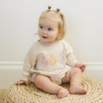 Long-sleeve sweatshirt romper with screenprinted retro daisy and ghost design and snaps at the crotch.