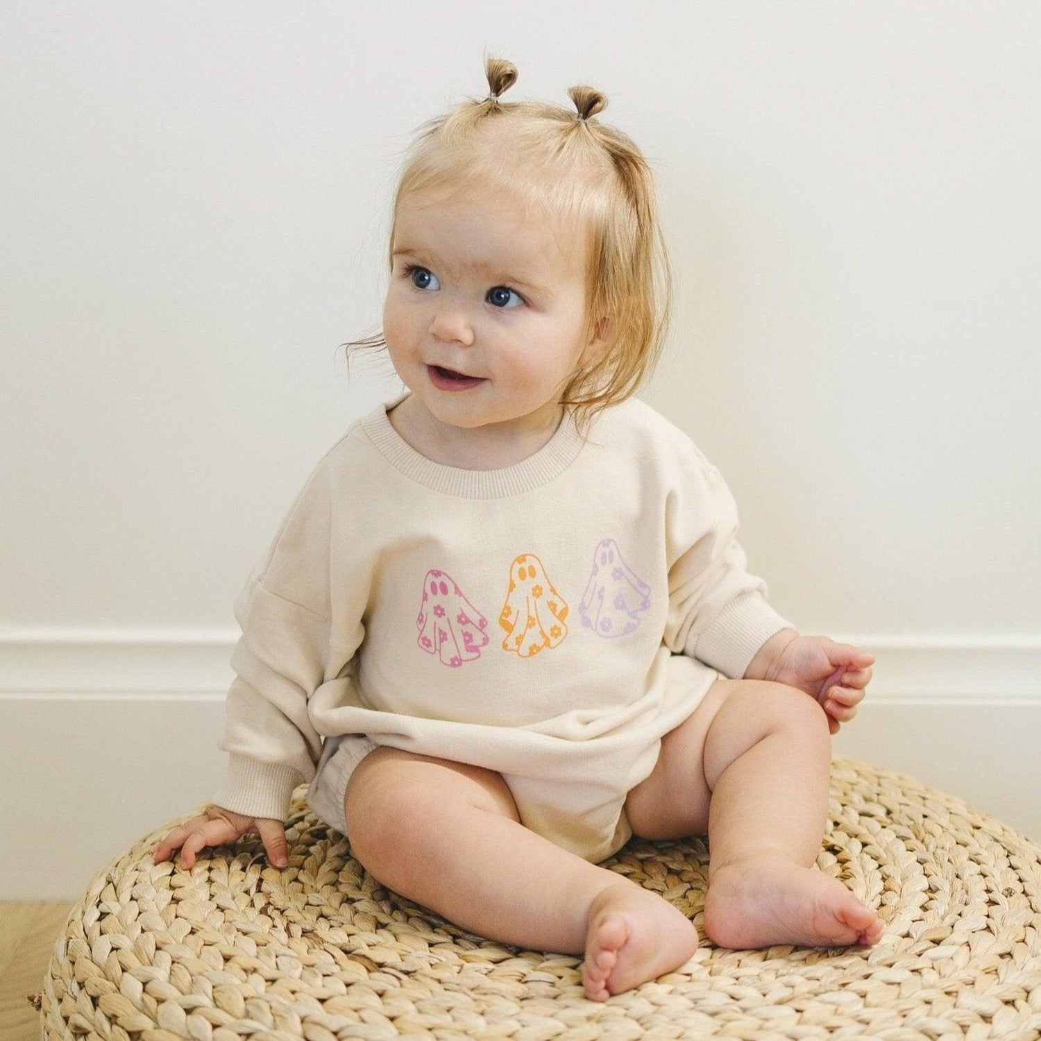 Long-sleeve sweatshirt romper with screenprinted retro daisy and ghost design and snaps at the crotch.