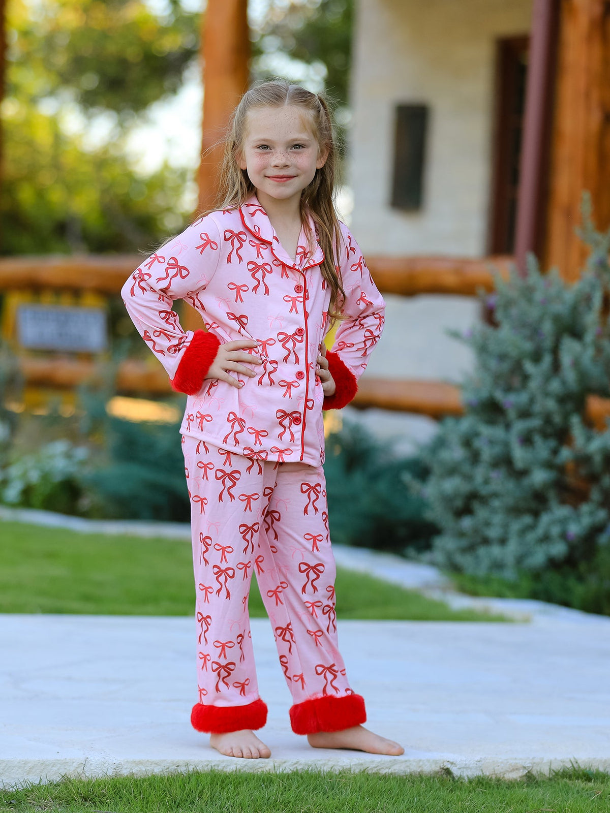 Girls two-piece Christmas pajama set with bow print and furry trim along the cuffs and hem