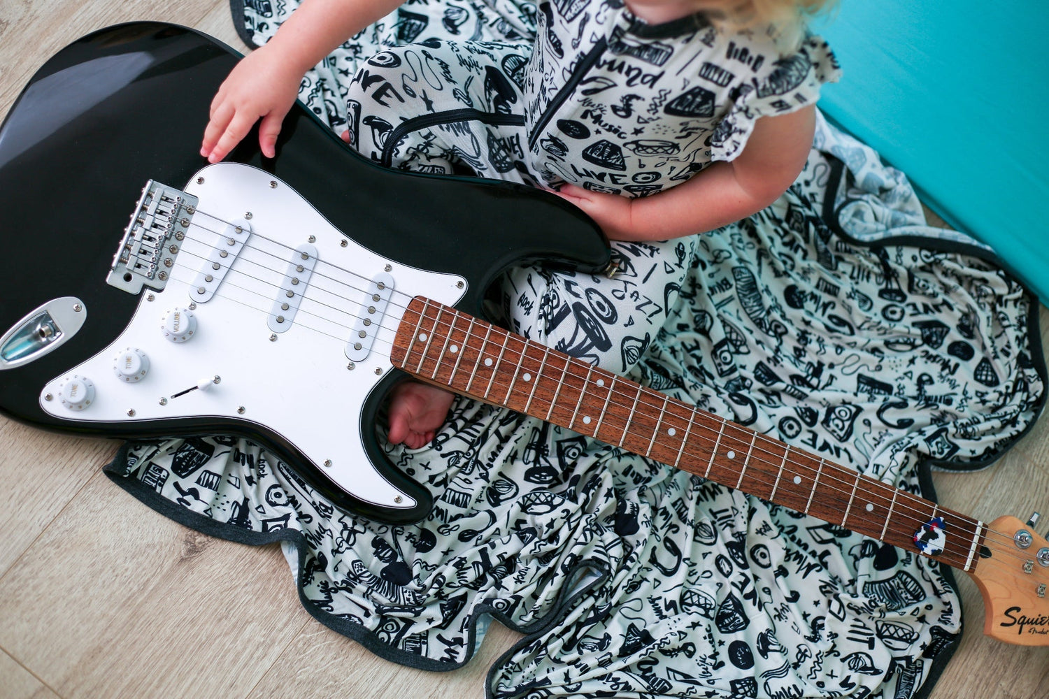 Baby swaddle blanket with an electric guitar print, shown spread out flat.