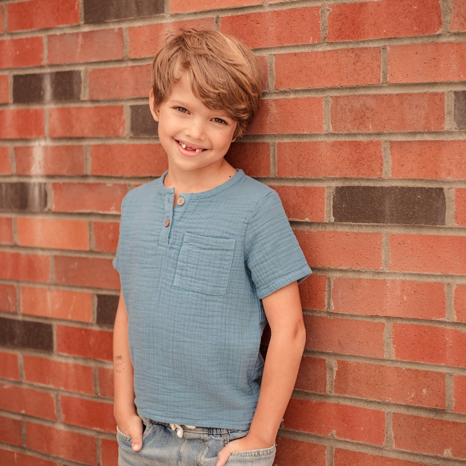 Blue henley button-down shirt for a child, made of soft gauze fabric with a chest pocket.
