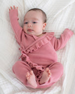 Baby wrap romper in dusty rose with ruffle trim along the neckline and wrap front, tied at the side