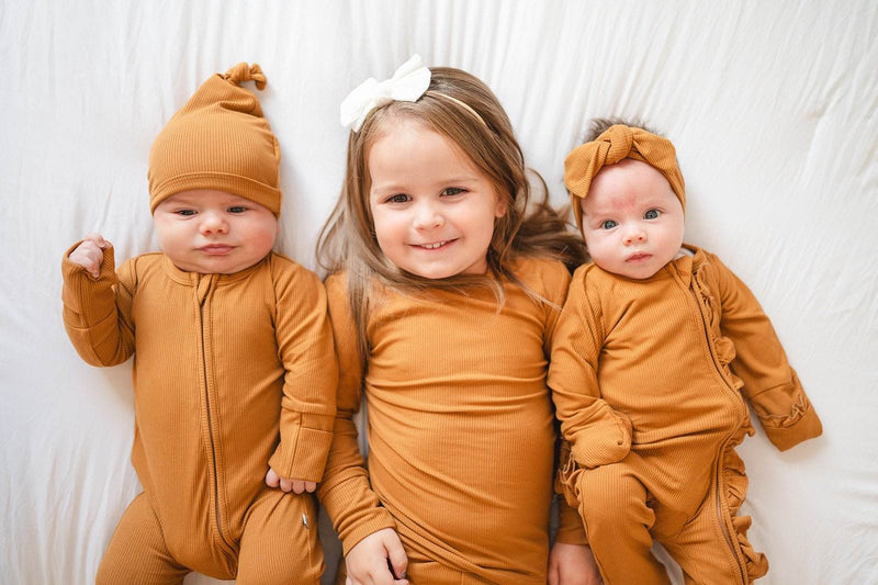 Ruffle Zipper One Piece in caramel ribbed fabric with ruffle details, featuring a 2-way zipper and fold-over hands and feet for babies.