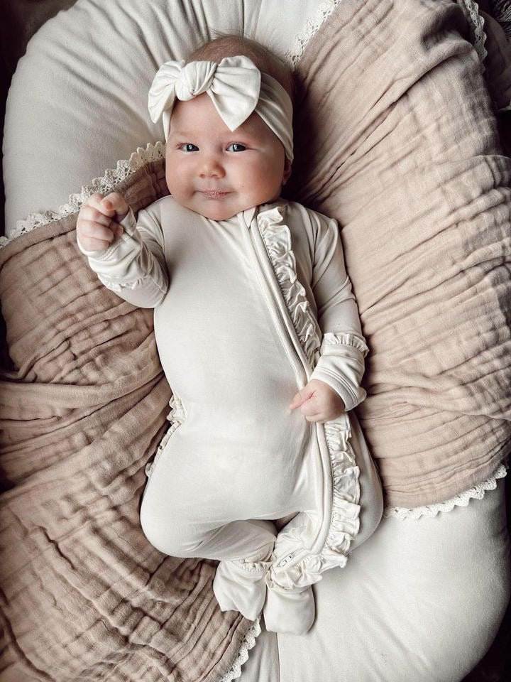 Cream ruffle zipper one piece baby outfit made from bamboo viscose, featuring a front zipper and fold-over cuffs.