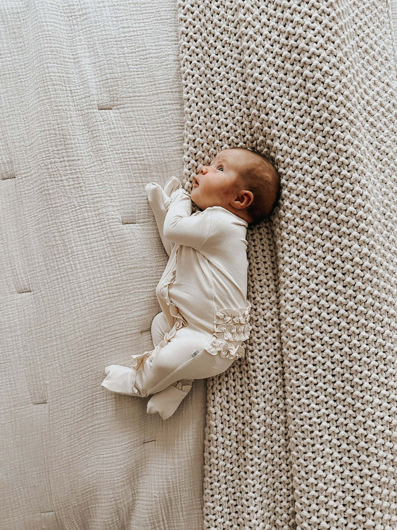 Cream ruffle zipper one piece outfit for baby with bamboo viscose material.