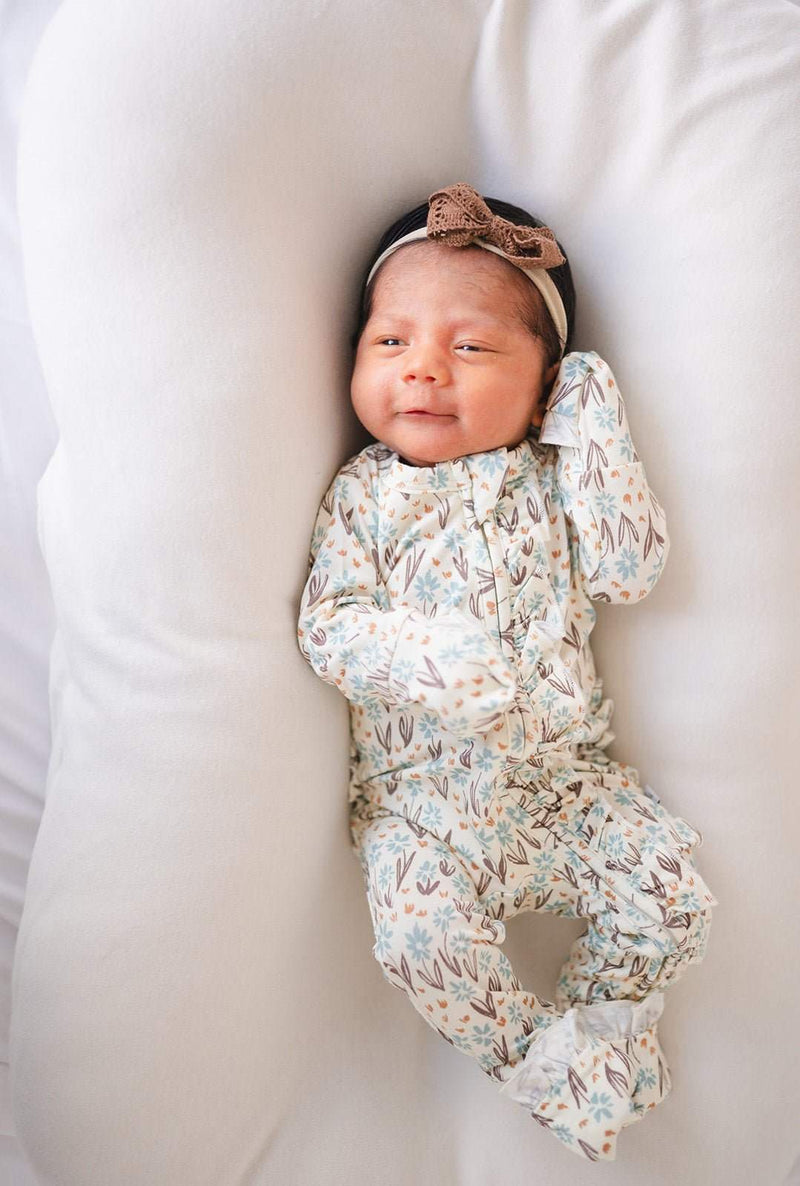 Ruffle zipper one piece in La La Floral design with ruffle details, worn by a baby.