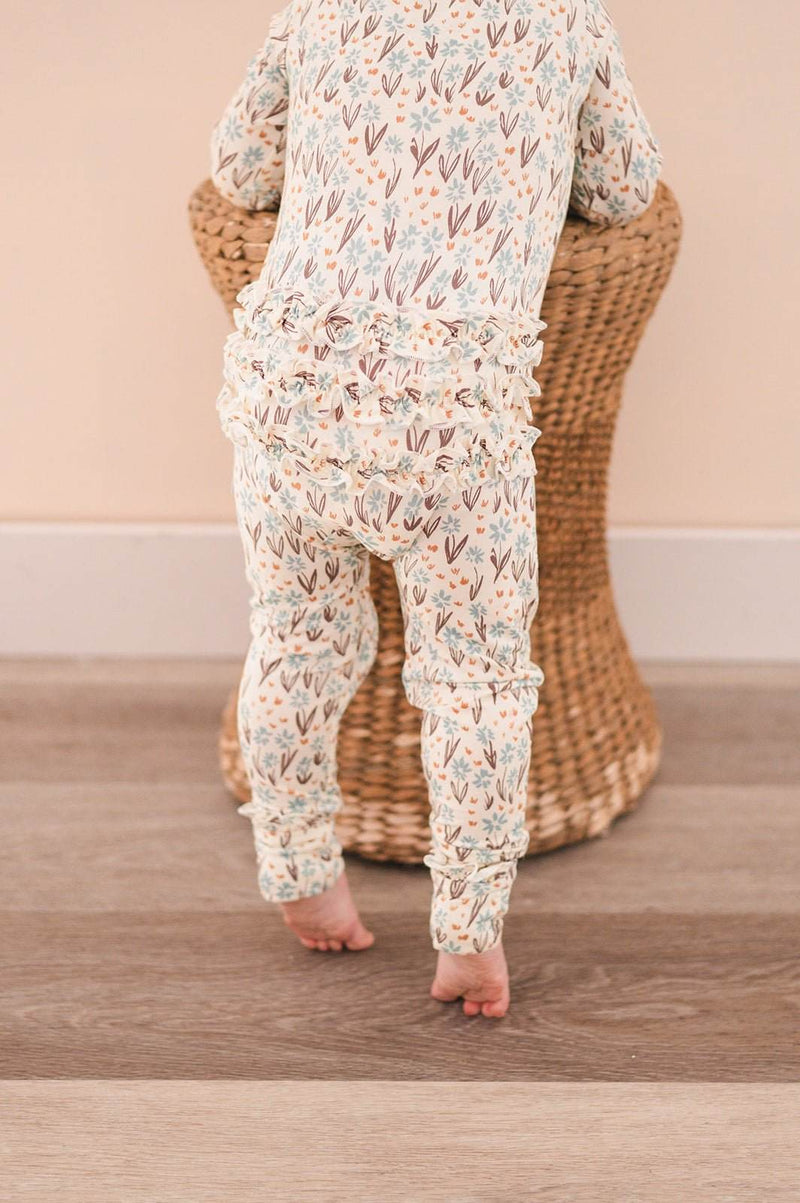 Ruffle Zipper One Piece in La La Floral with ruffle details and fold-over feet.