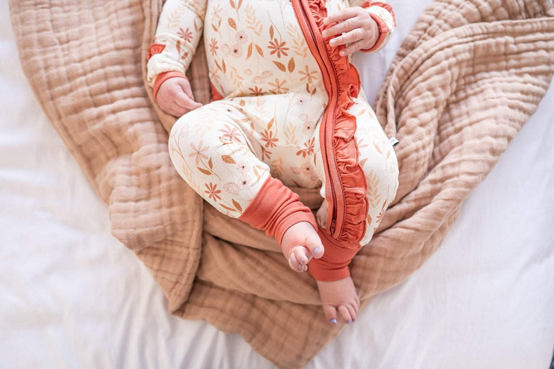 Baby wearing a Wildflower Ruffle Zipper One Piece with floral design, showcasing ruffle details and a zipper closure.