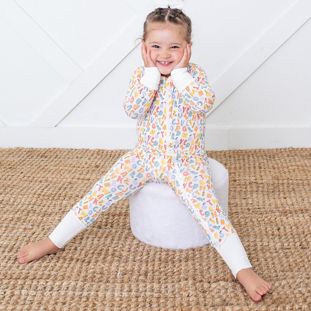 Baby coverall in a playful scribbled alphabet print with long sleeves, footed legs, and a full-length 2-way zipper.