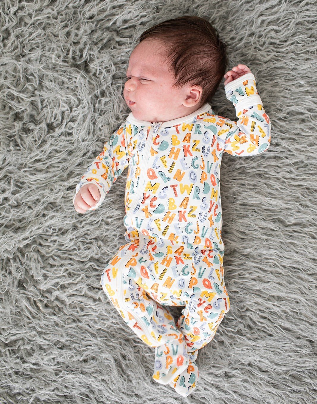 Baby footie pajamas with a scribble print and a two-way zipper running from neck to feet.