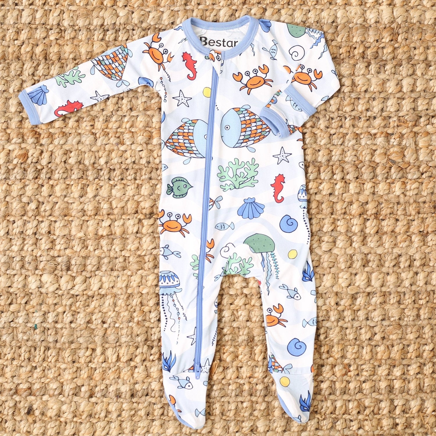 Baby footie pajamas in a sea life swirl print with blue and orange creatures and a full-length zipper.