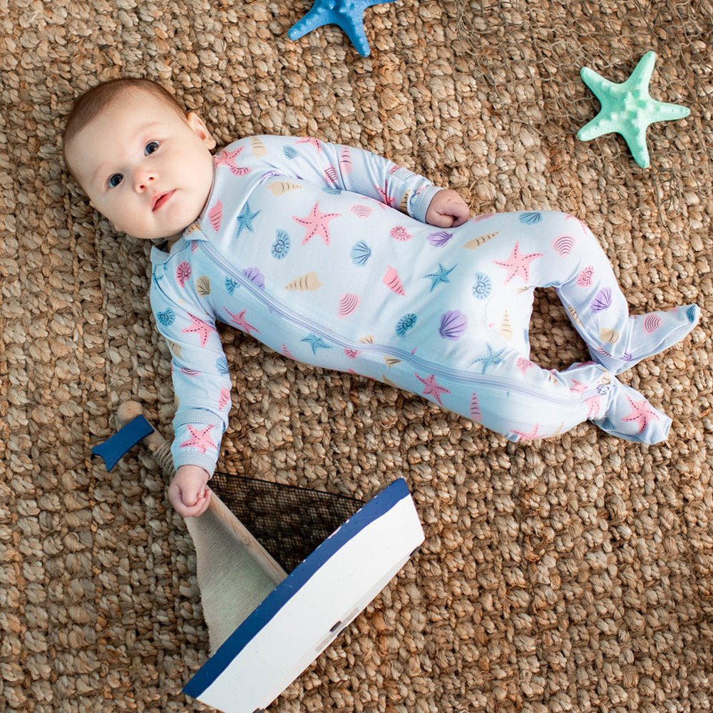 Baby footie pajamas in a seashell and sea star print with a full-length two-way zipper and footed legs.