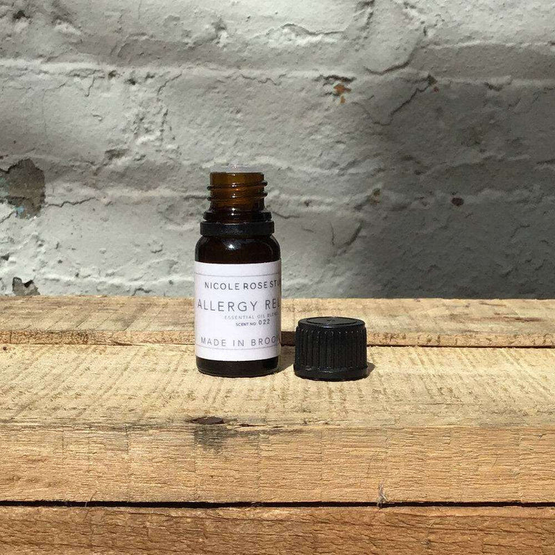 Essential oil bottle labeled "Allergy Relief" on wooden surface, therapeutic-grade blend for seasonal spring relief.