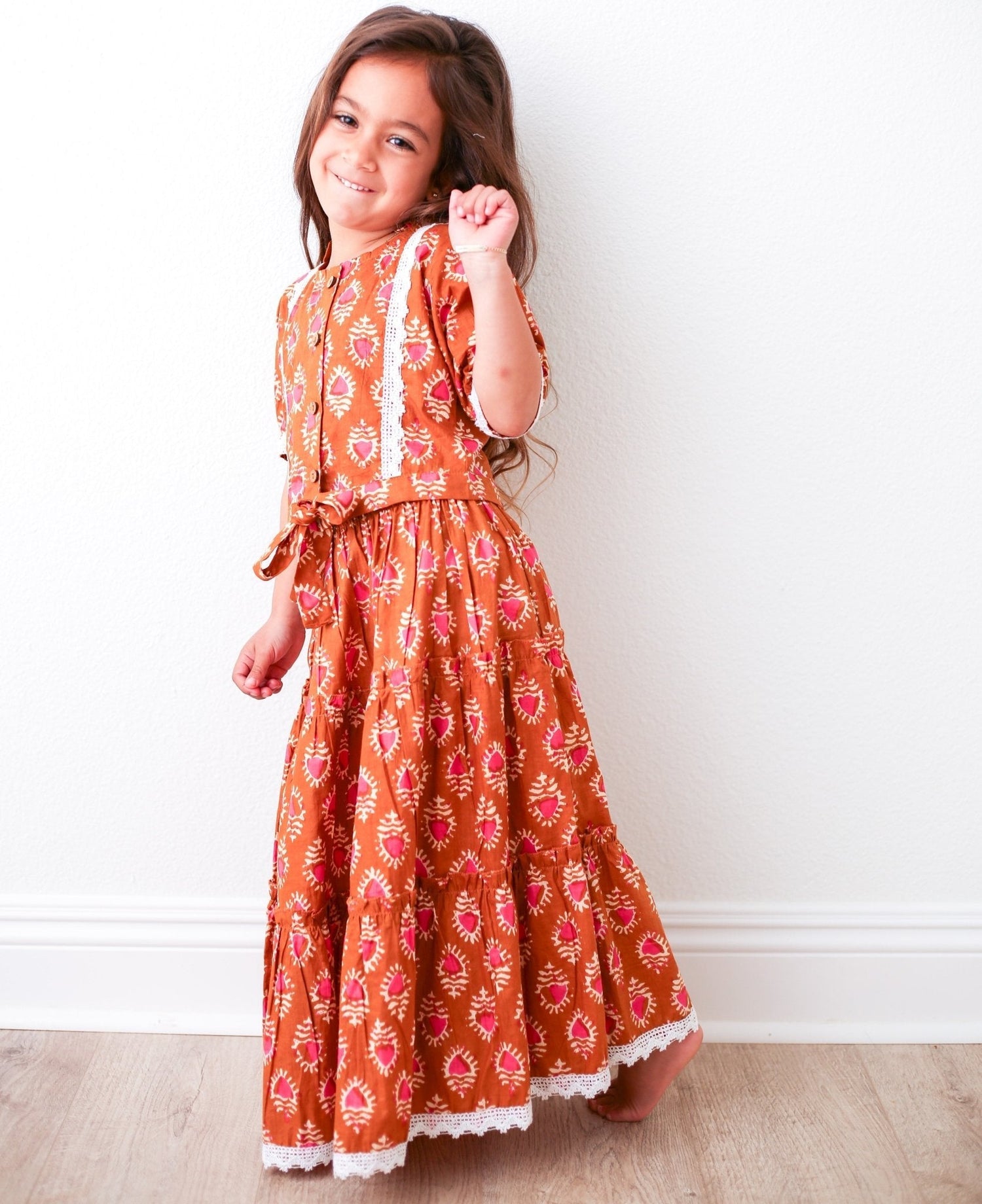 Rust-colored girls lehenga skirt with matching top featuring lace detailing and wooden buttons.