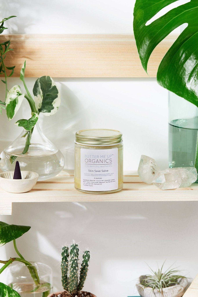 Organic Skin Save Salve jar on a shelf with plants and crystals.