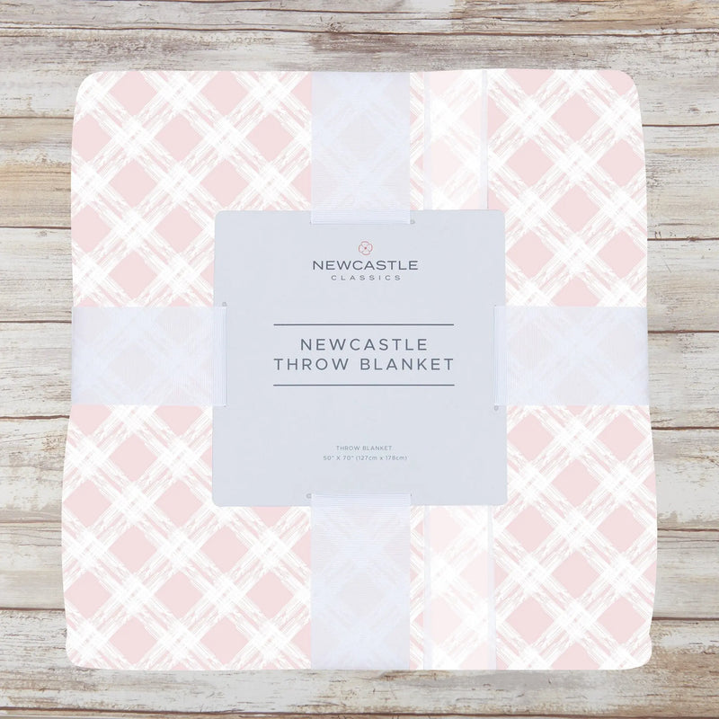 Primrose Pink Plaid Cotton Muslin Throw Blanket on a wooden surface.