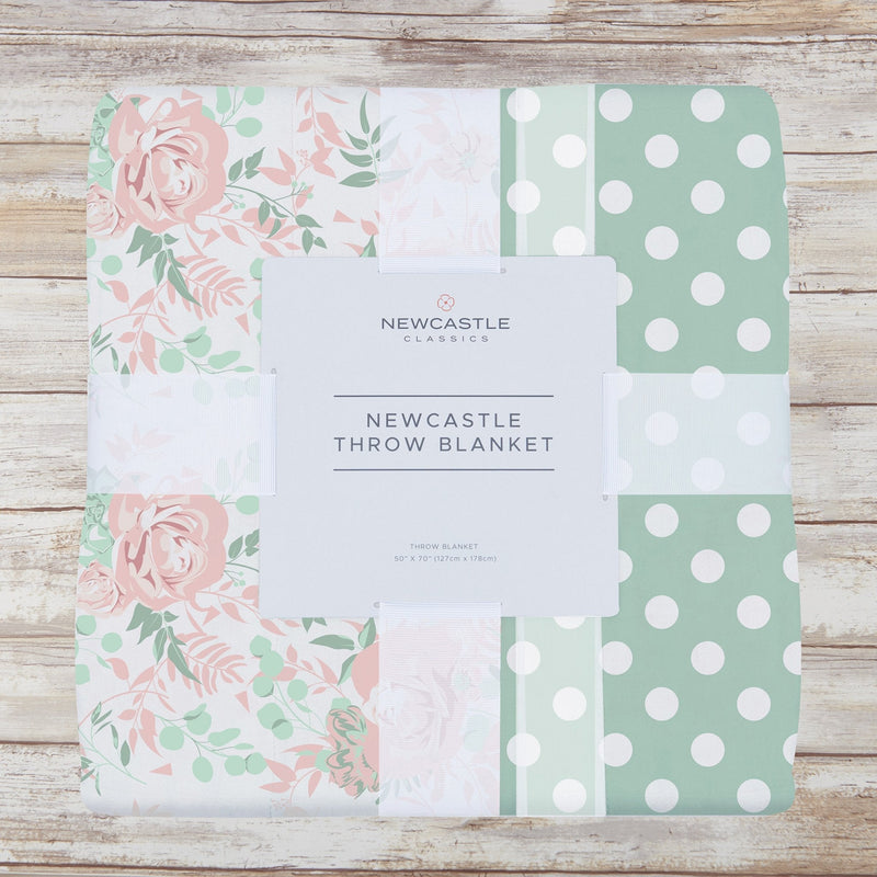 Desert Rose and Jade polka dot cotton muslin throw blanket on wood background.