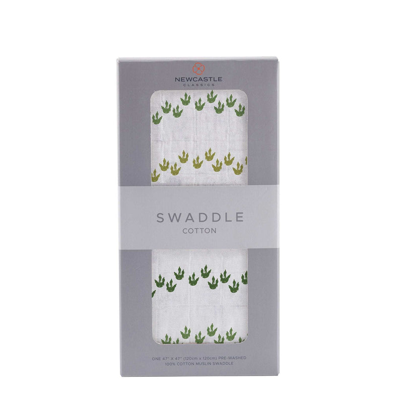 Dino Feet Cotton Muslin Swaddle in packaging with green dinosaur footprints design.