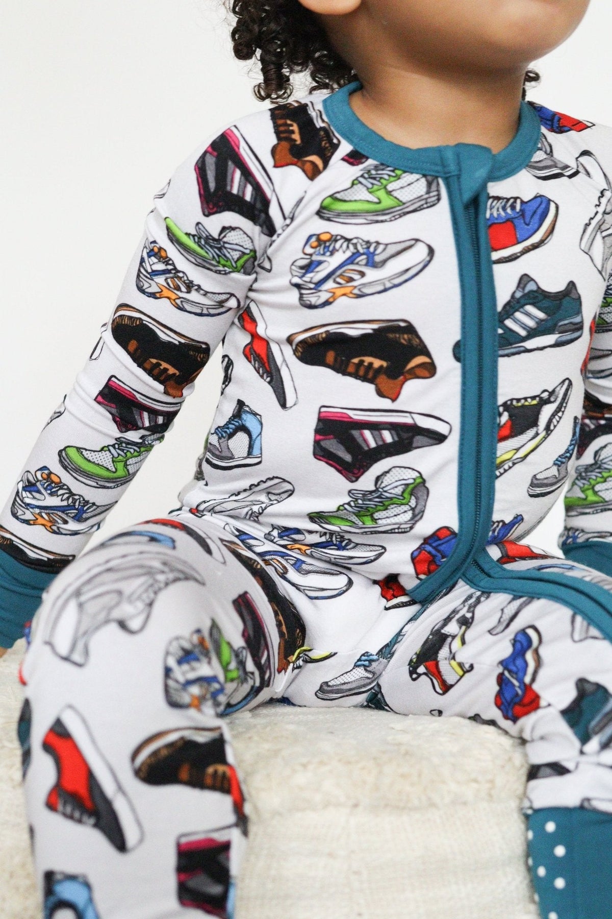 Baby zip-up romper in a sneaker print with fold-over feet and mittens.