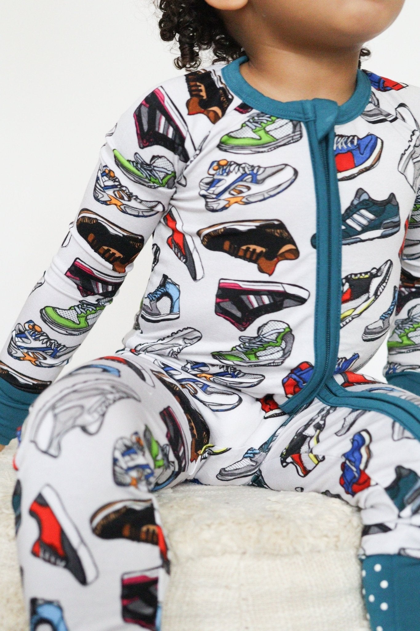 Baby zip-up romper in a sneaker print with fold-over feet and mittens.
