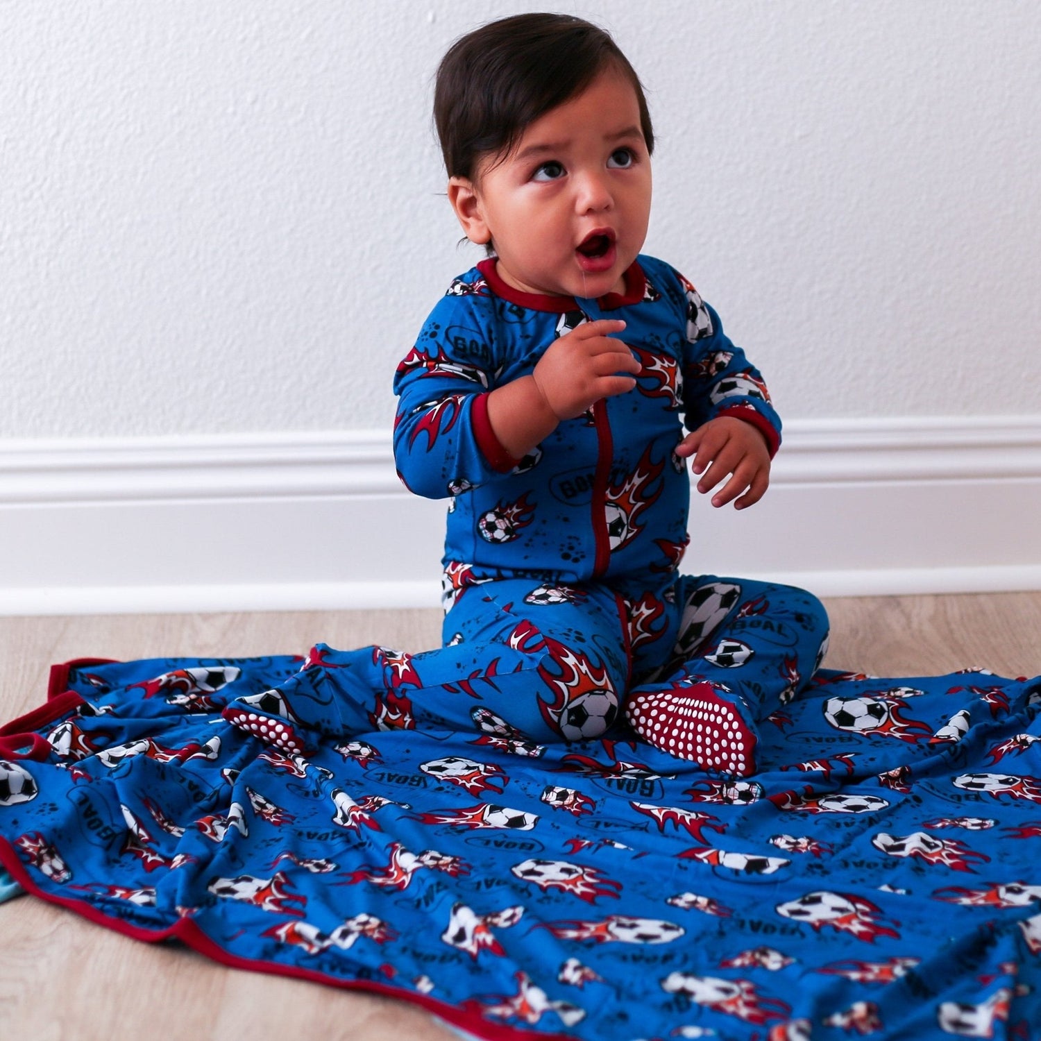 Baby footie pajamas in a soccer ball print with fold-over mittens, foot grips, and a full-length dual zipper.