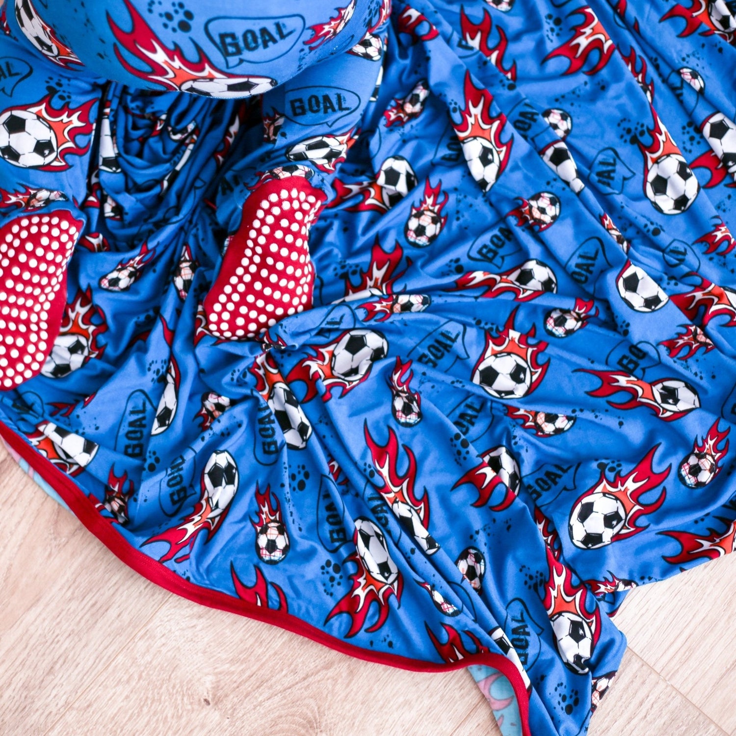 Baby swaddle blanket with a soccer ball pattern, spread flat and square