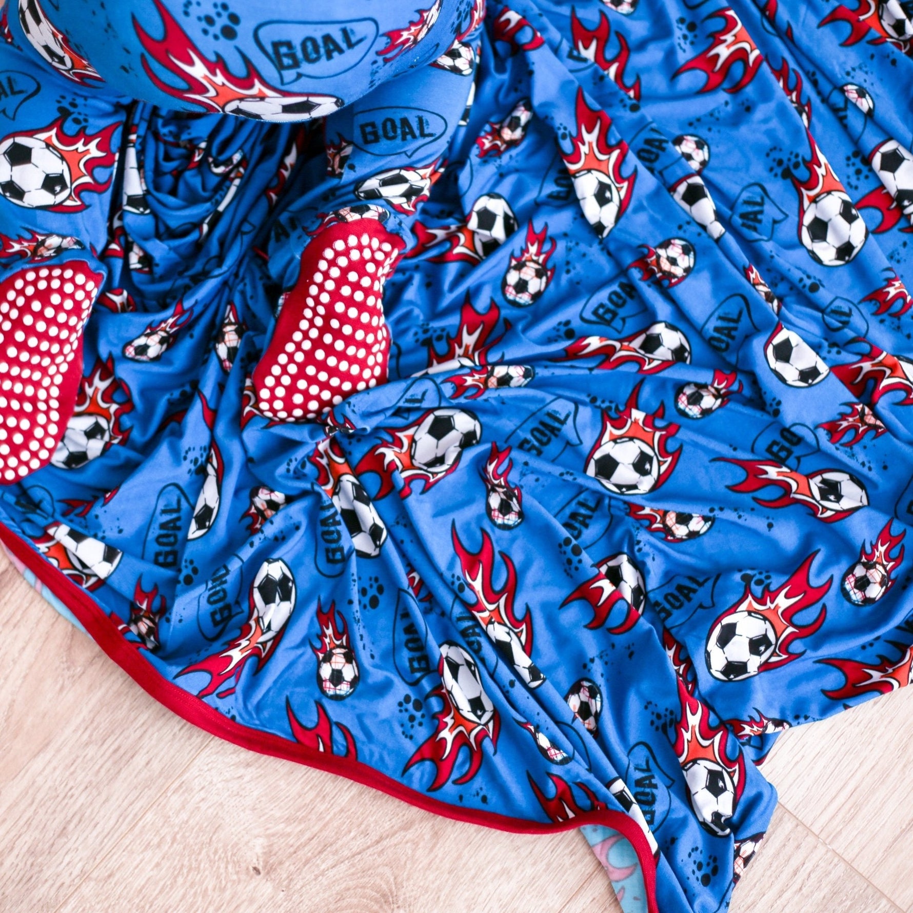 Baby swaddle blanket with a soccer ball pattern, spread flat and square
