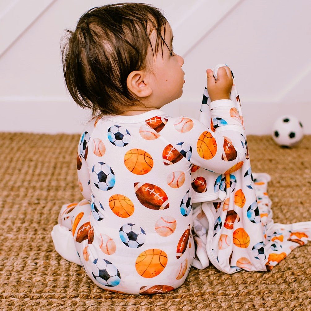 Baby footie pajamas with an all-over sports print and a full-length front zipper.