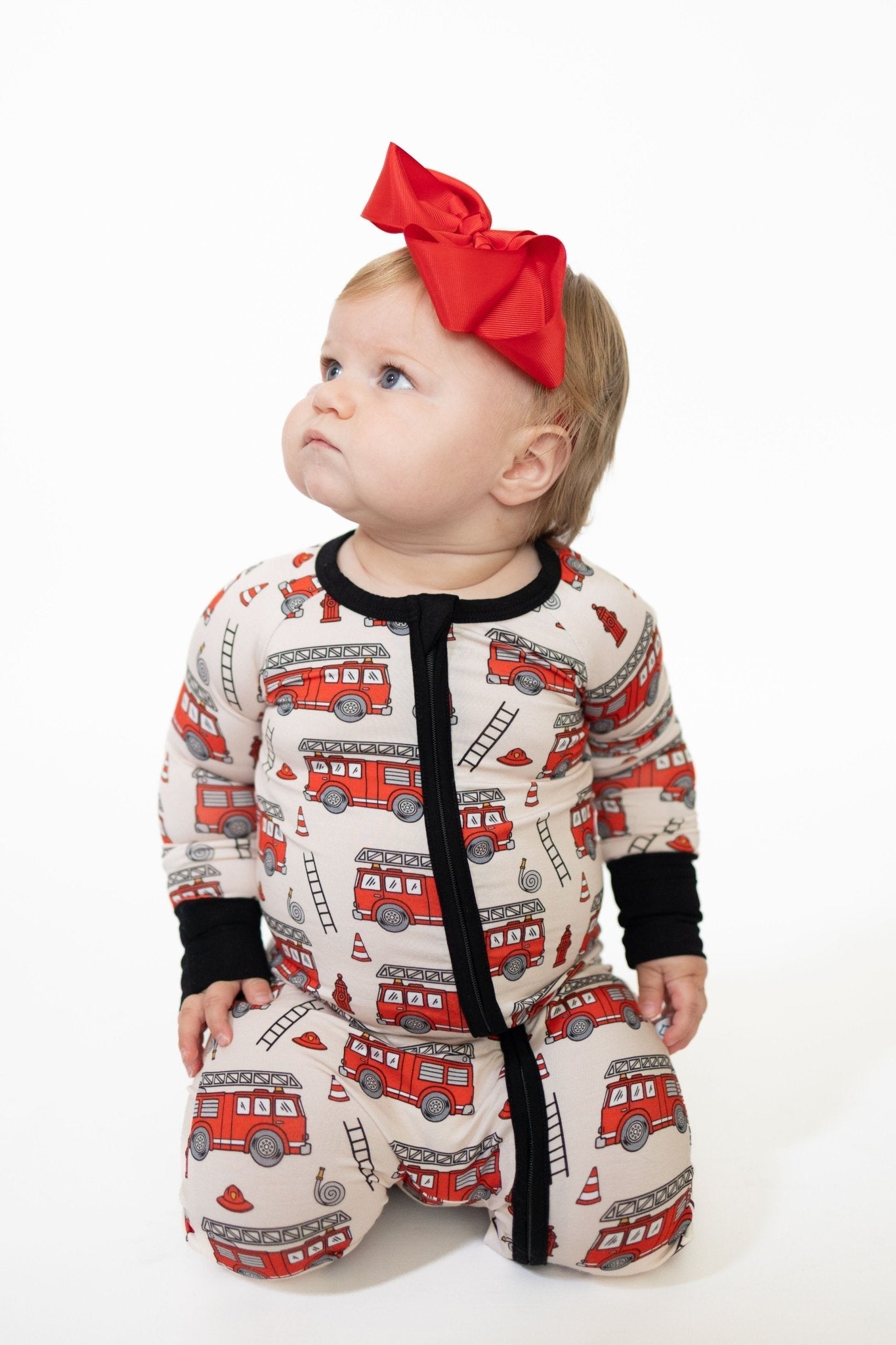 Baby zip-up bamboo pajamas with fold-over feet in a bold red firetruck print for infants.