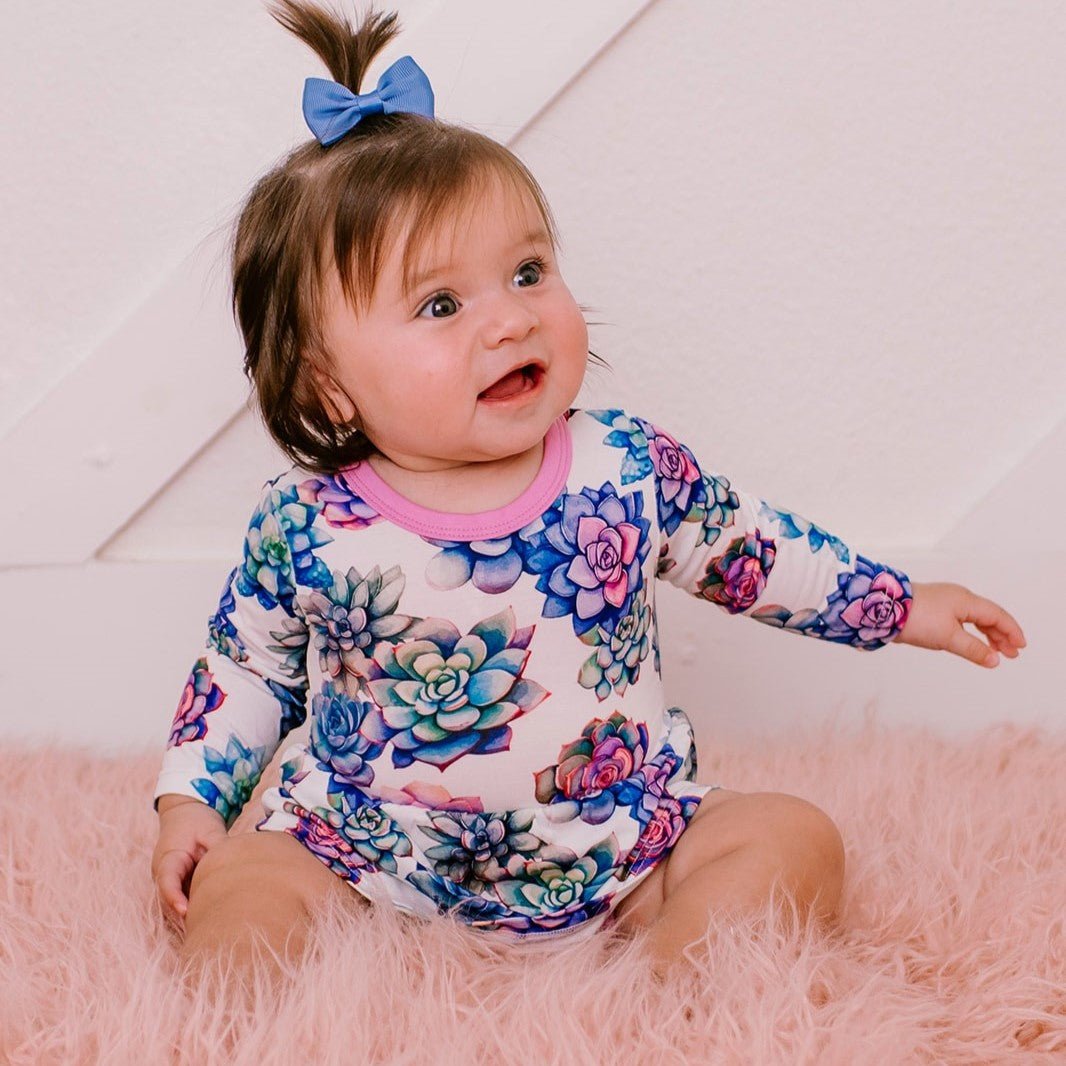Long-sleeve bodysuit dress with a pink succulent heart print on a baby.