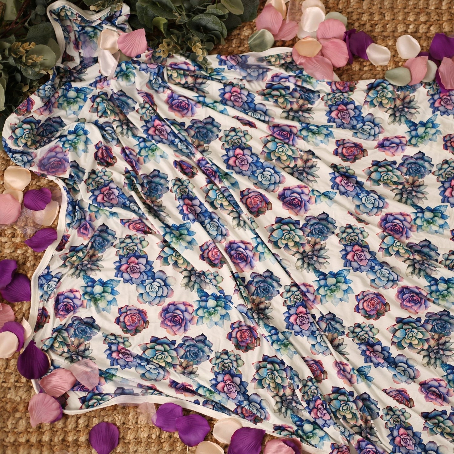 Swaddle blanket with pink and purple succulent print, spread flat to show the square shape.