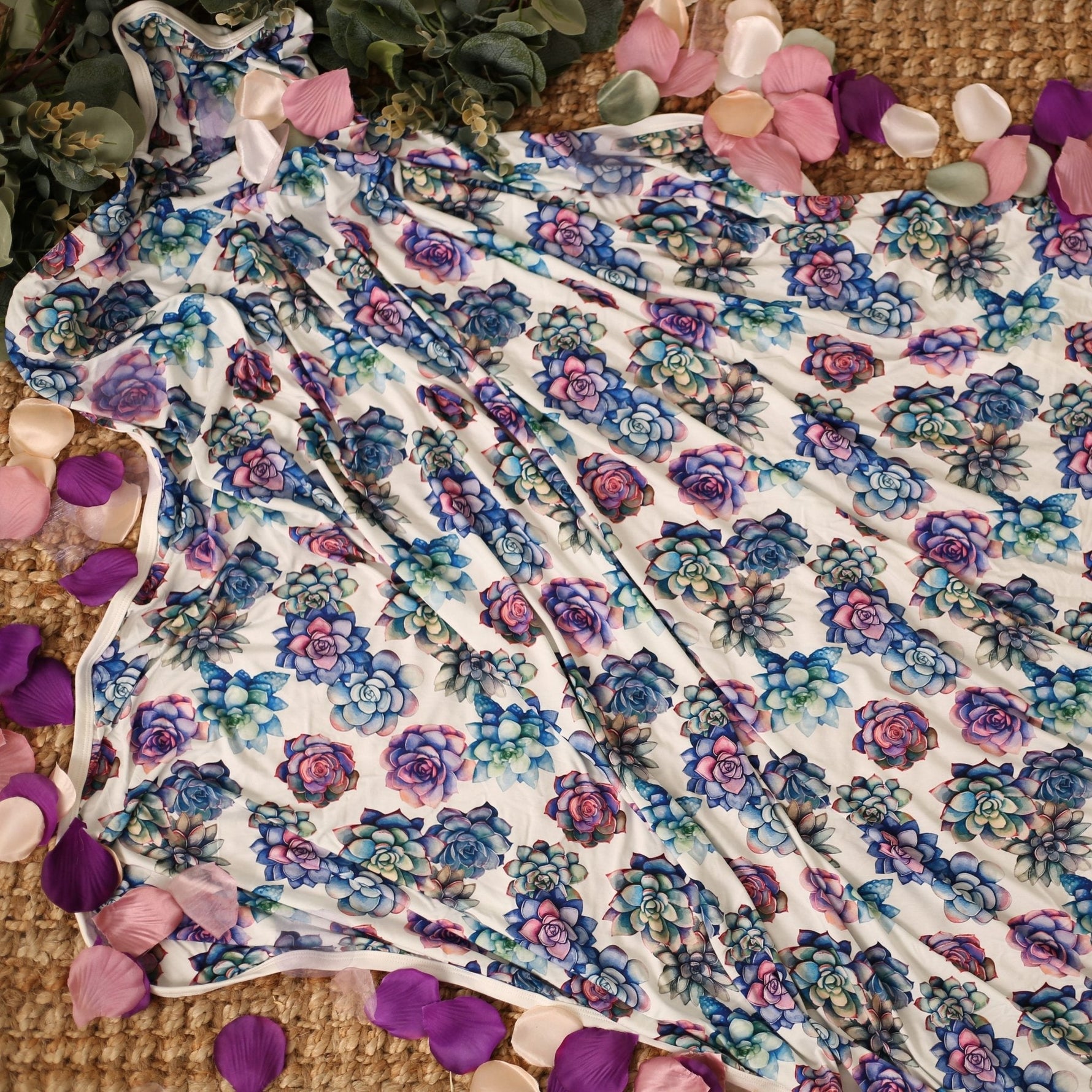 Swaddle blanket with pink and purple succulent print, spread flat to show the square shape.