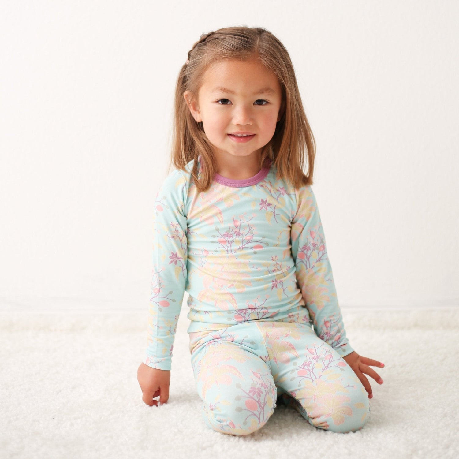 Two-piece baby pajama set in aqua with a summer floral pattern, long-sleeve top and matching pants.