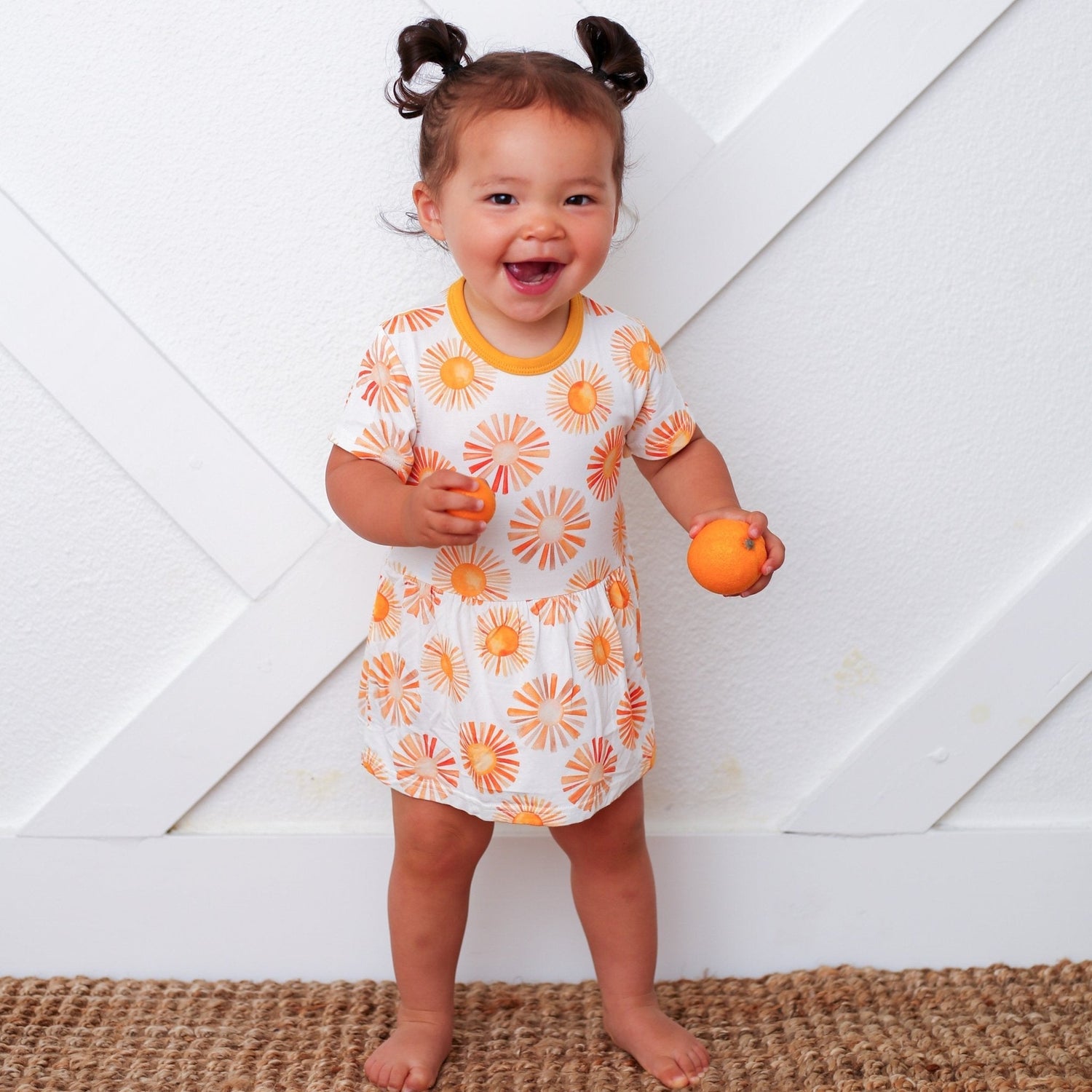 Bodysuit dress with a colorful sun print, short sleeves, and snap closures at the inseam.