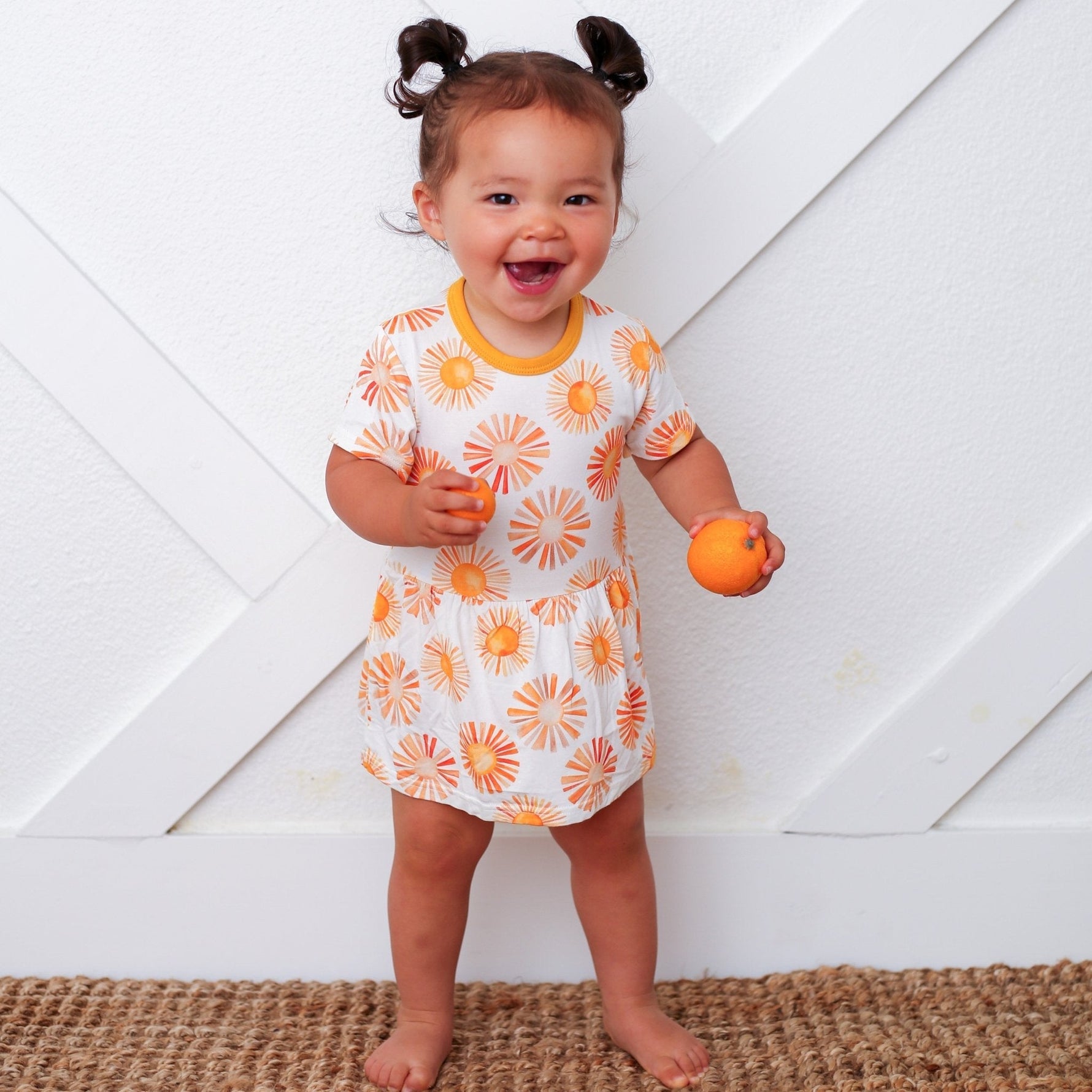 Bodysuit dress with a colorful sun print, short sleeves, and snap closures at the inseam.