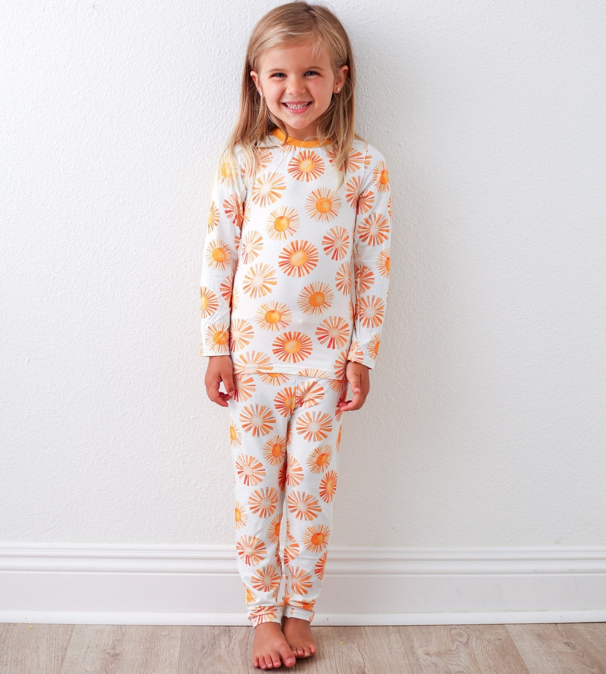 Toddler pajama set with top and pants printed in a bright, colorful sun pattern