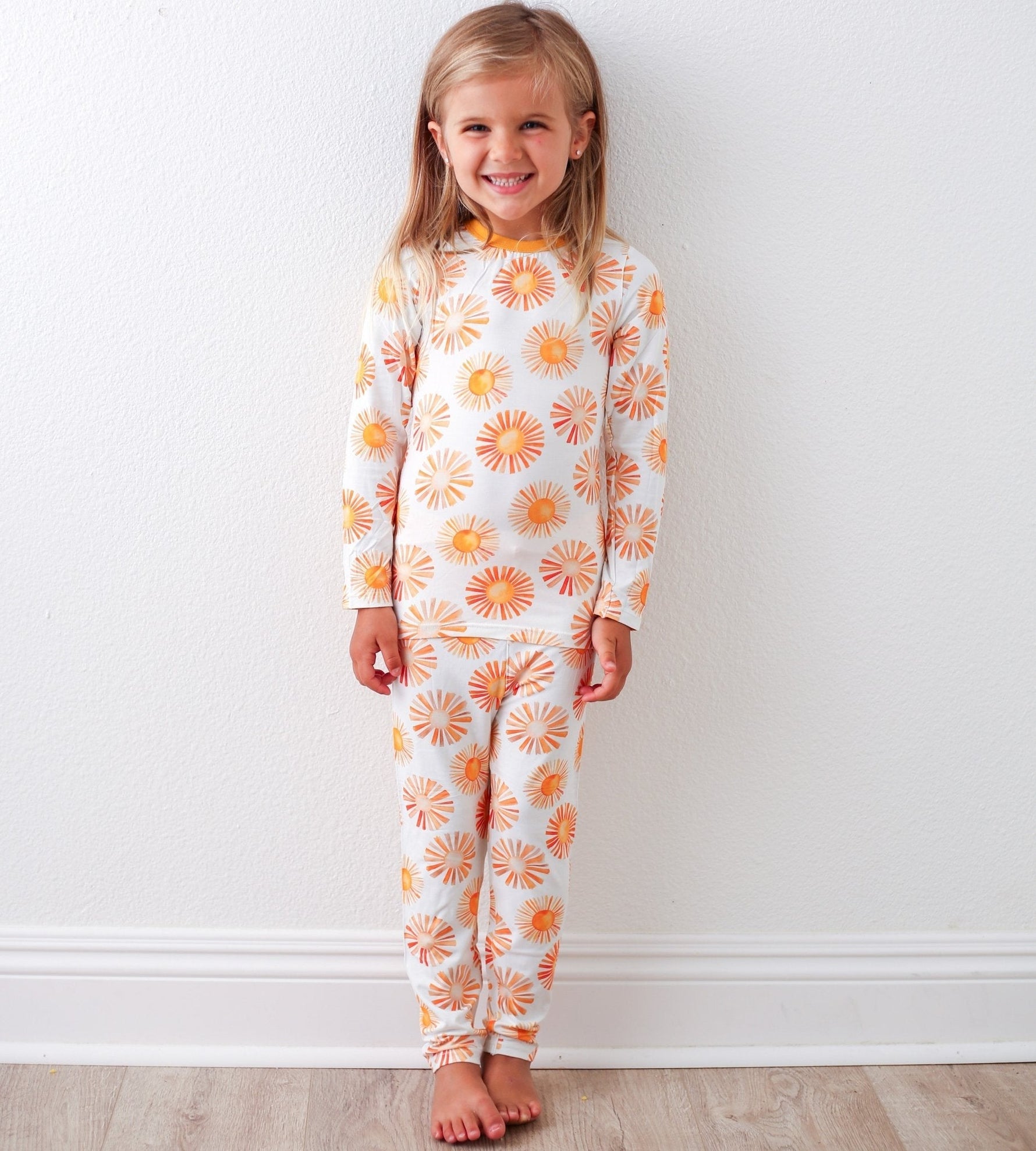 Toddler pajama set with top and pants printed in a bright, colorful sun pattern
