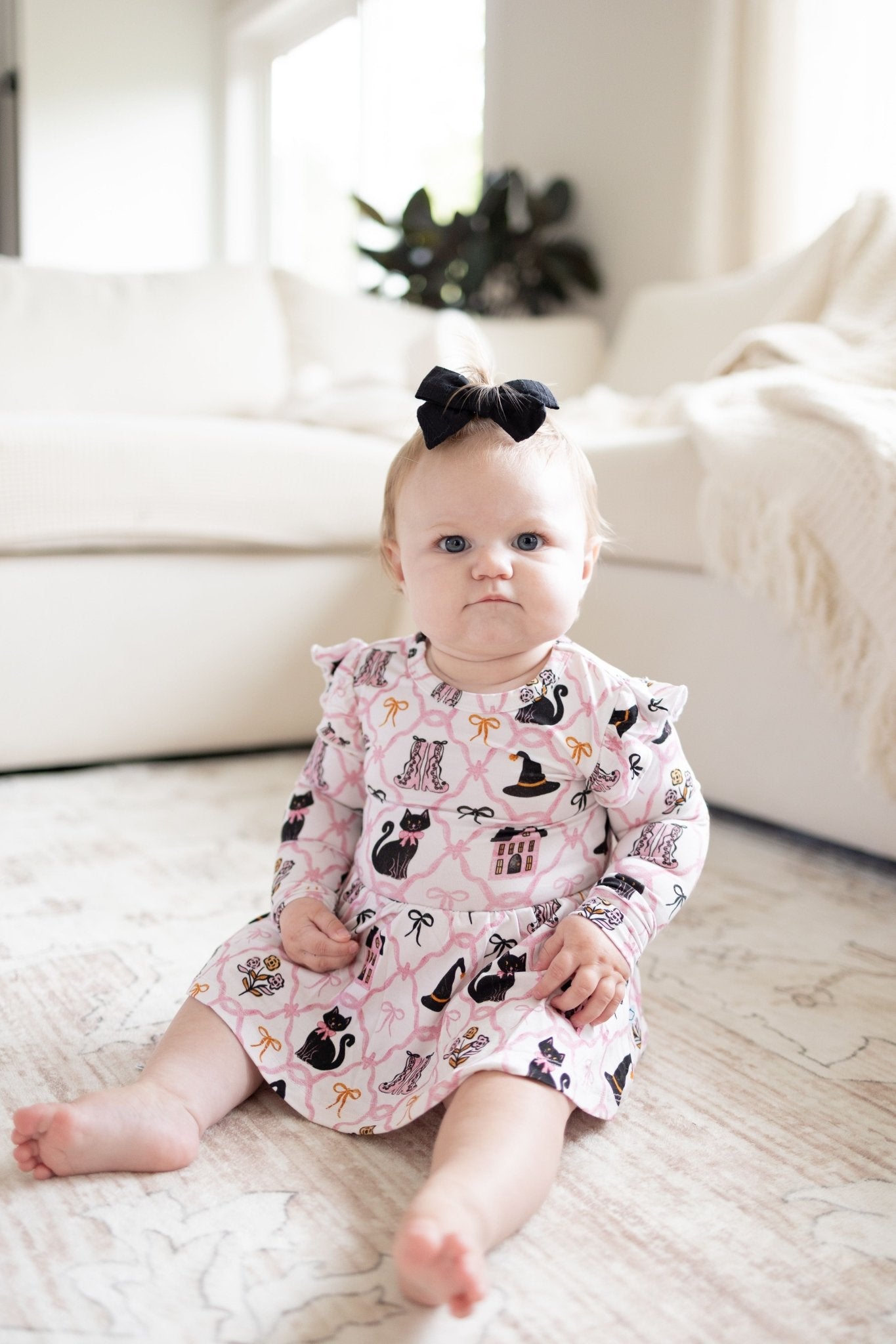 Bodysuit twirl dress in soft pink with black cats and witch hats, flutter cap sleeves and a built-in snap bodysuit.