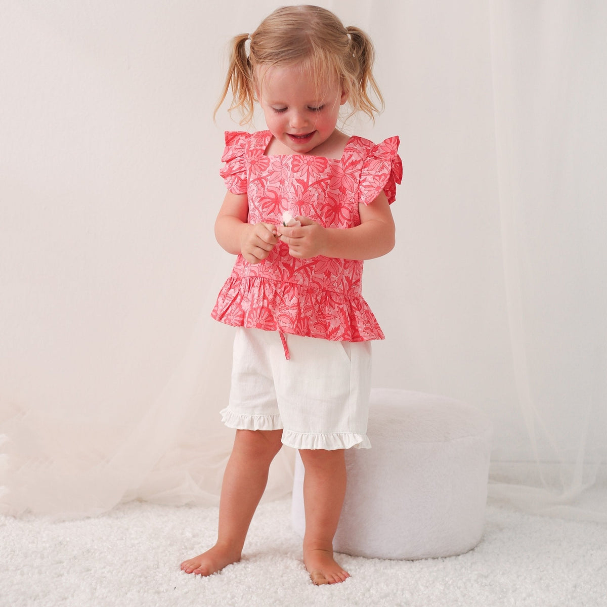 Girls' pink two-piece set with flutter-sleeve top and matching shorts, worn by a child model.