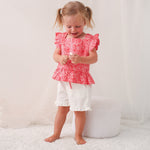 Girls' pink two-piece set with flutter-sleeve top and matching shorts, worn by a child model.