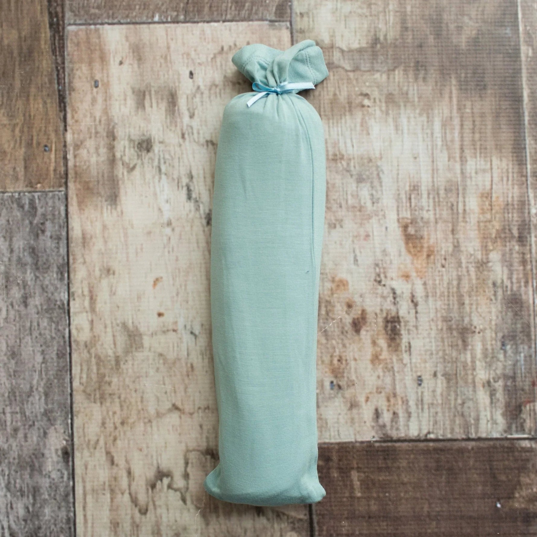 Teal swaddle blanket with a rope pattern, spread flat to show the square shape