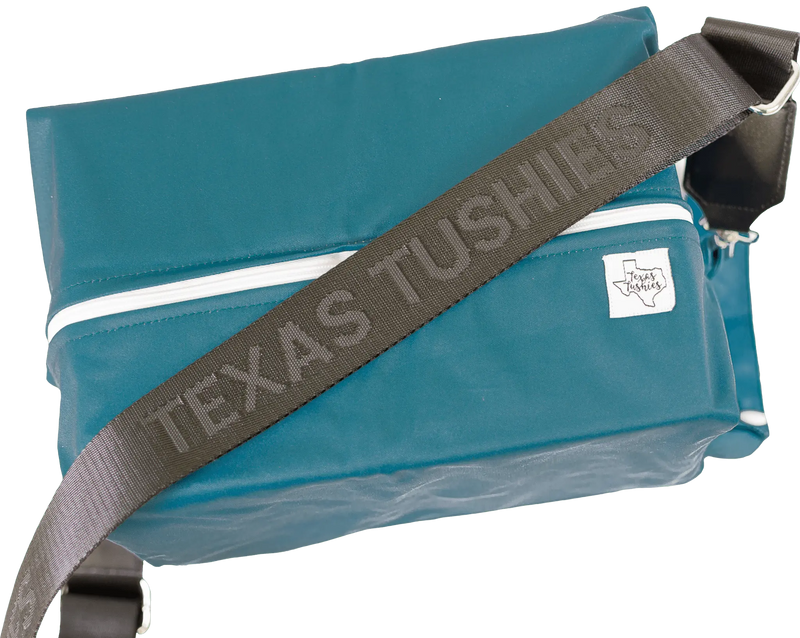 Texas Tushies Exclusive Pod Strap with black adjustable design and silver hardware attached to a blue bag.