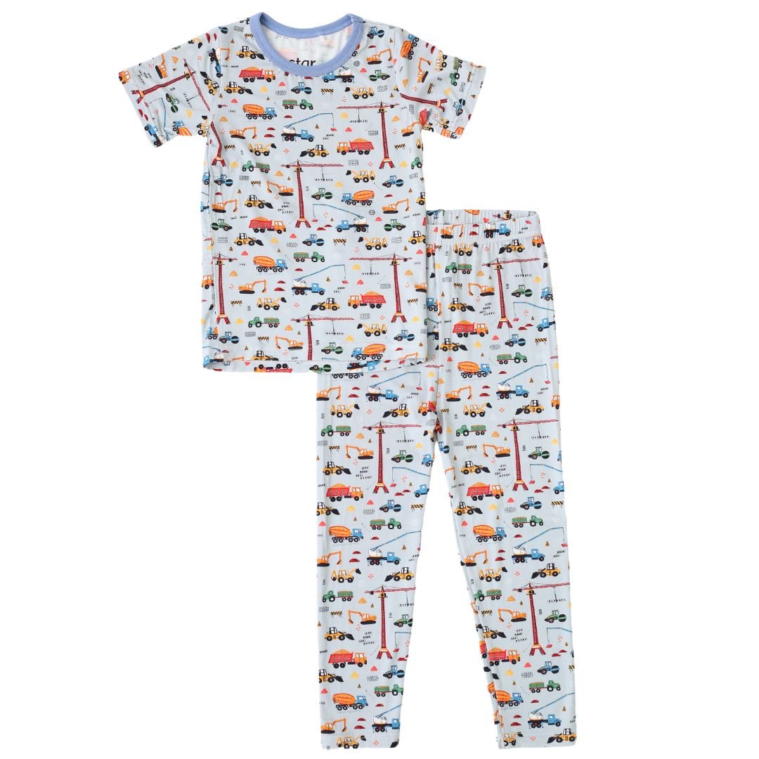 Short sleeve baby pajama set with a construction site print featuring trucks on the top and pants.