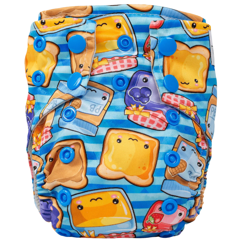 Tiny Tushies Newborn AIO Cloth Diaper with colorful cartoon print and blue snaps.