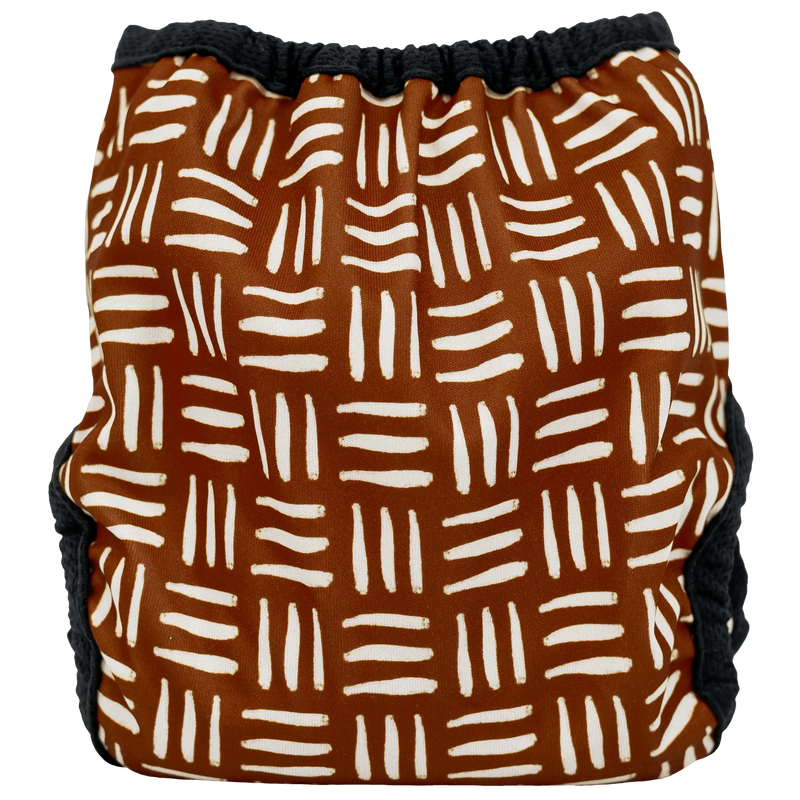 Tiny Tushies Newborn Hook & Loop Cover with geometric print, adjustable fit for babies 5-20 lbs, reusable wipeable PUL design.
