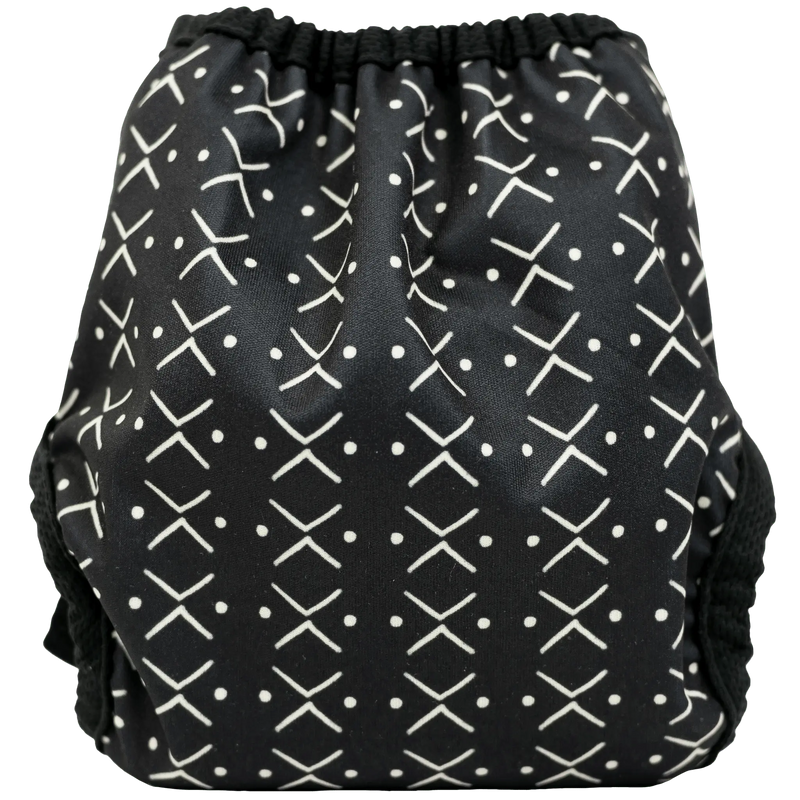 Tiny Tushies Newborn Hook & Loop Cover with geometric print, adjustable fit for 5-20 lbs babies.