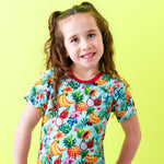 Baby pajamas with a tropical fruit print of pineapples and strawberries on a light background.