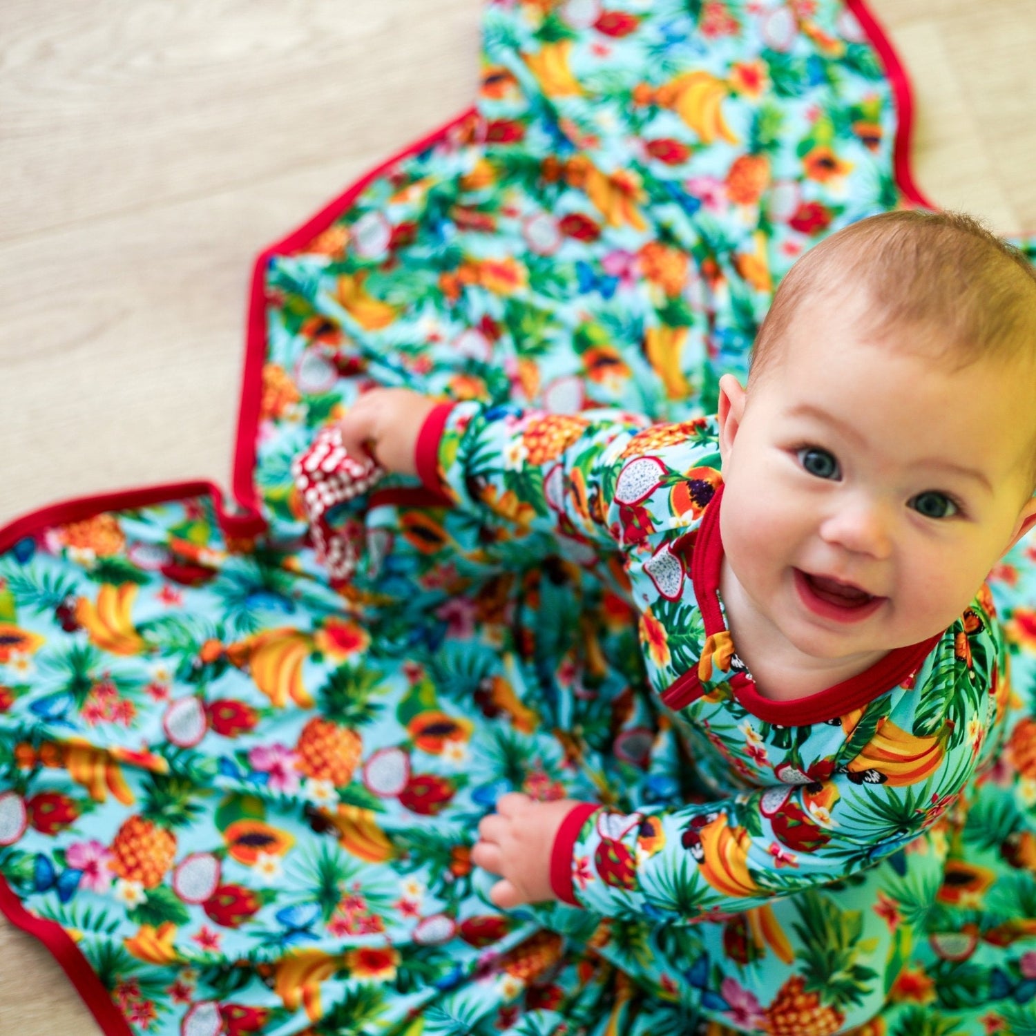 Swaddle blanket with a colorful tropical fruit print spread out flat